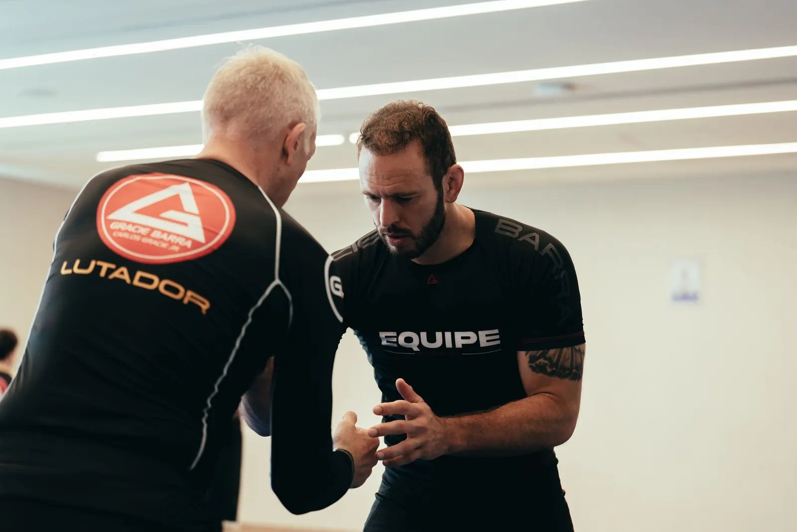 Two adult students discussing a Jiu-Jitsu technique on the mats
