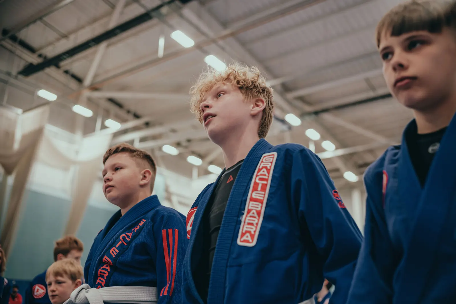 Children in blue Gracie Barra gis standing and listening