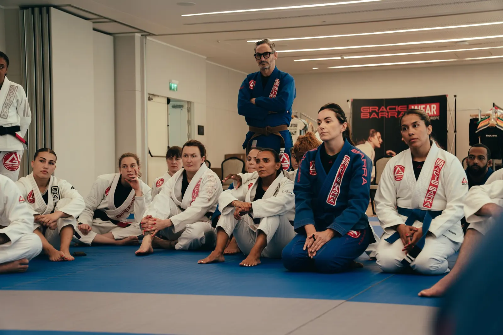 Adult students in Gracie Barra gis sitting and listening to instruction
