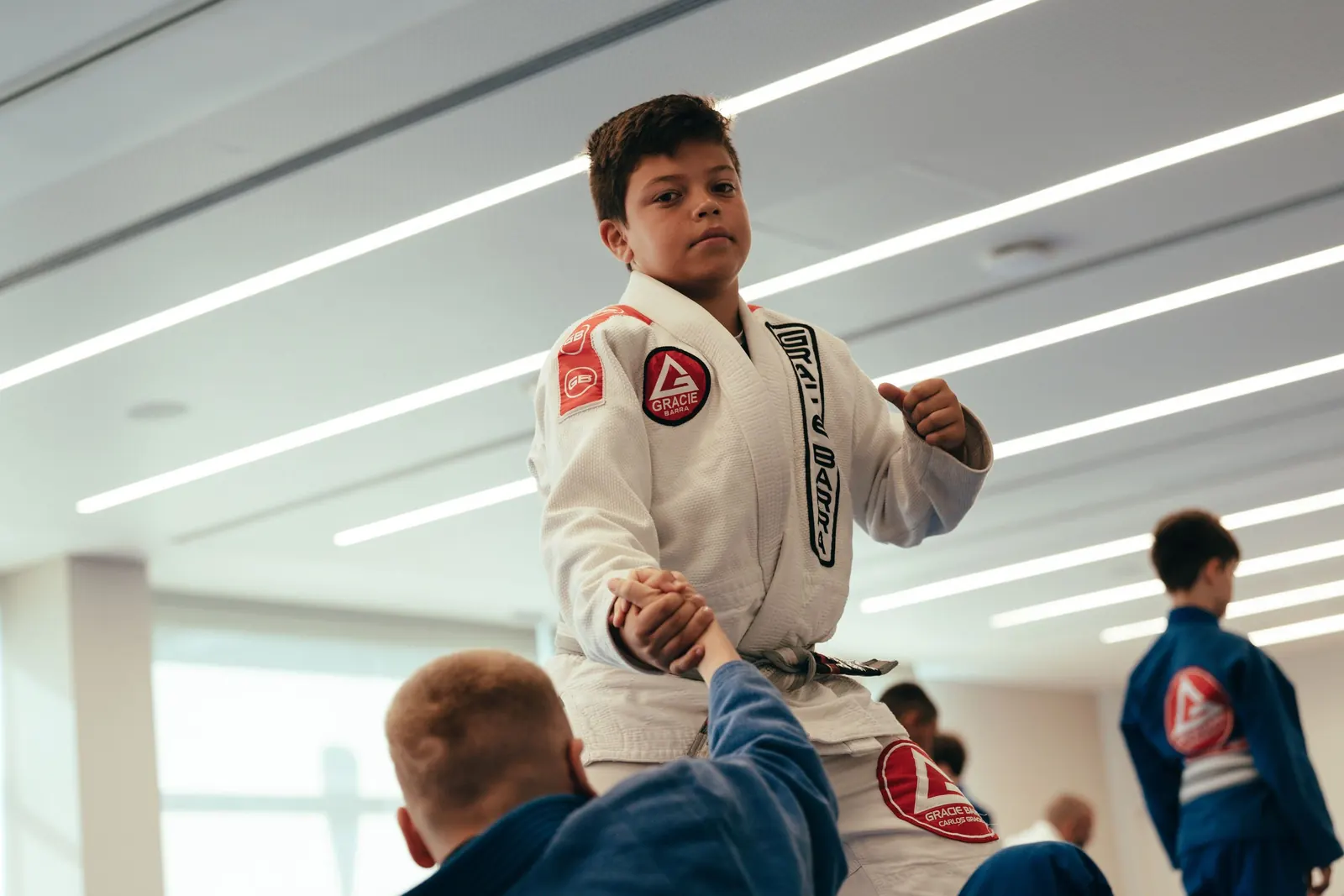 A young student in a white gi practising a movement with a partner