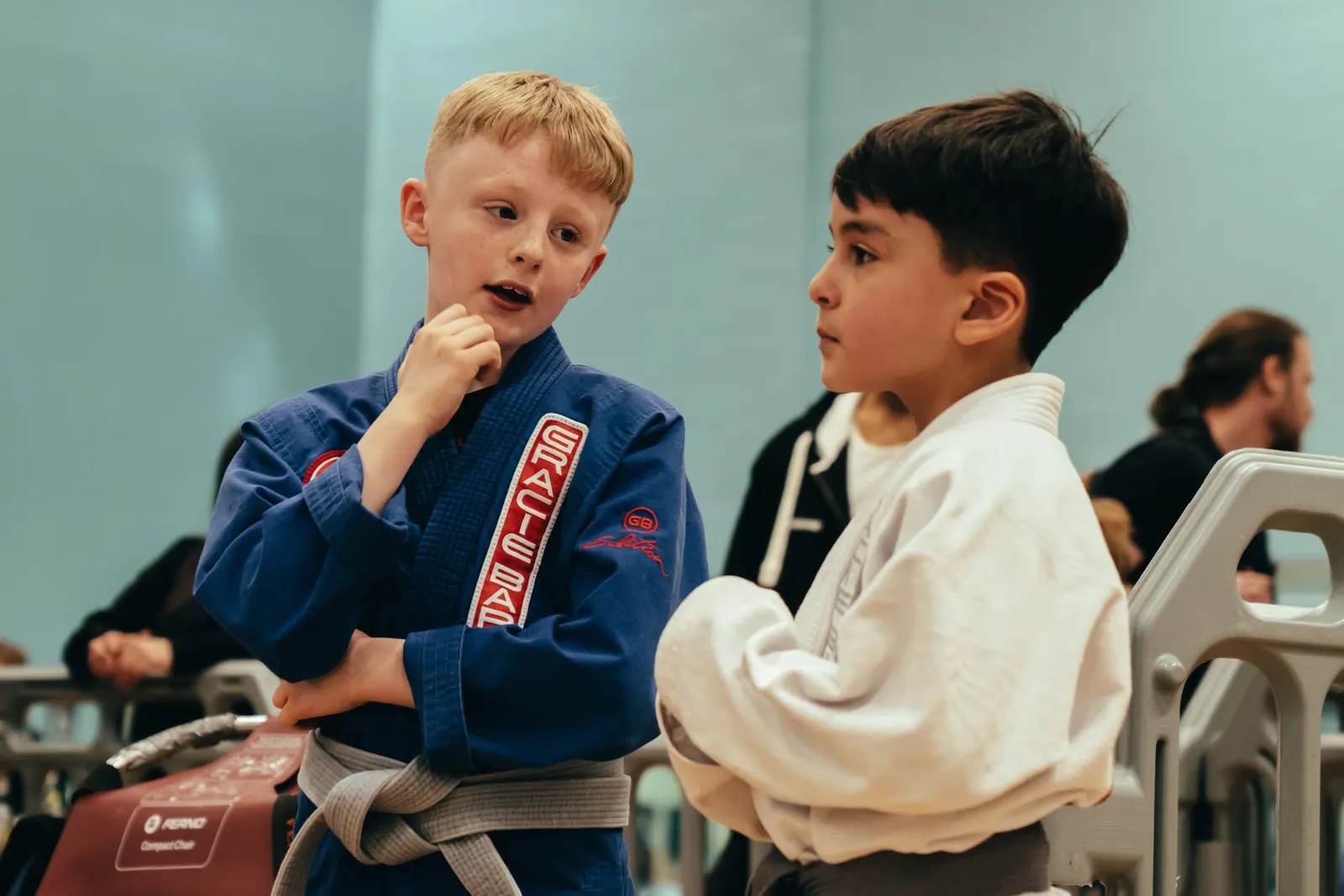 Two young students talking at the edge of the mat