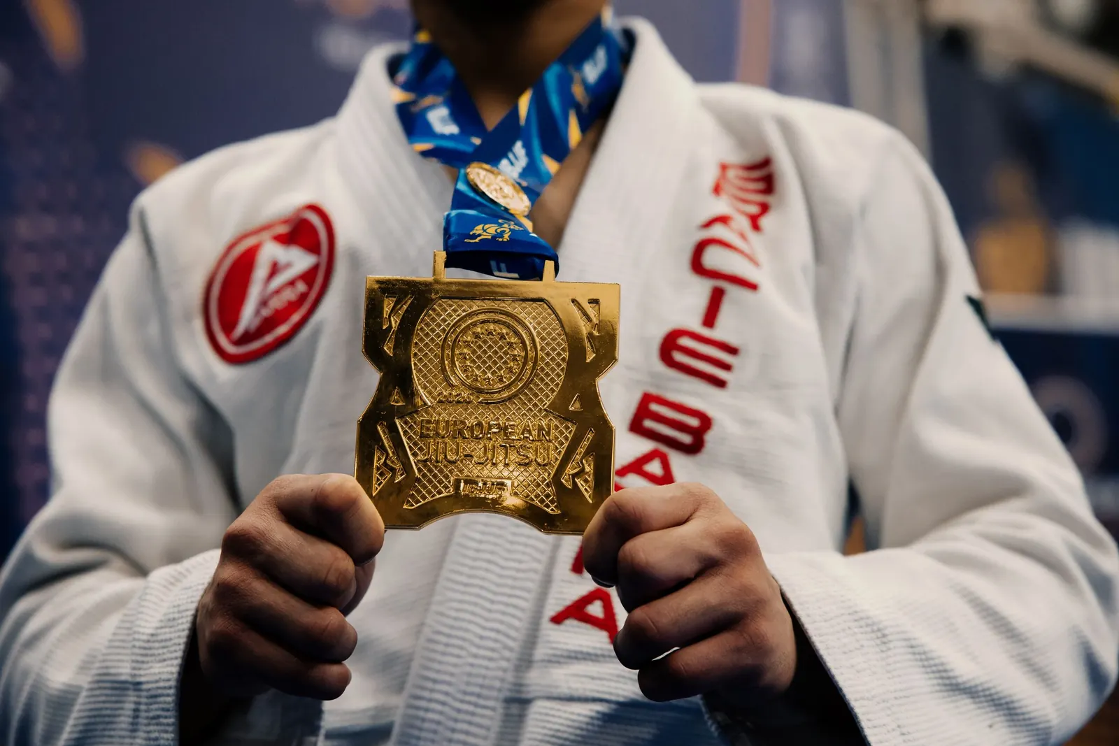 A student in a white Gracie Barra gi holding a European Jiu-Jitsu medal